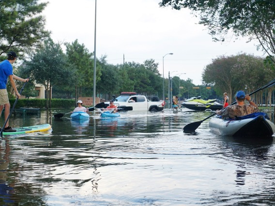 people kayaking on a flooded street
